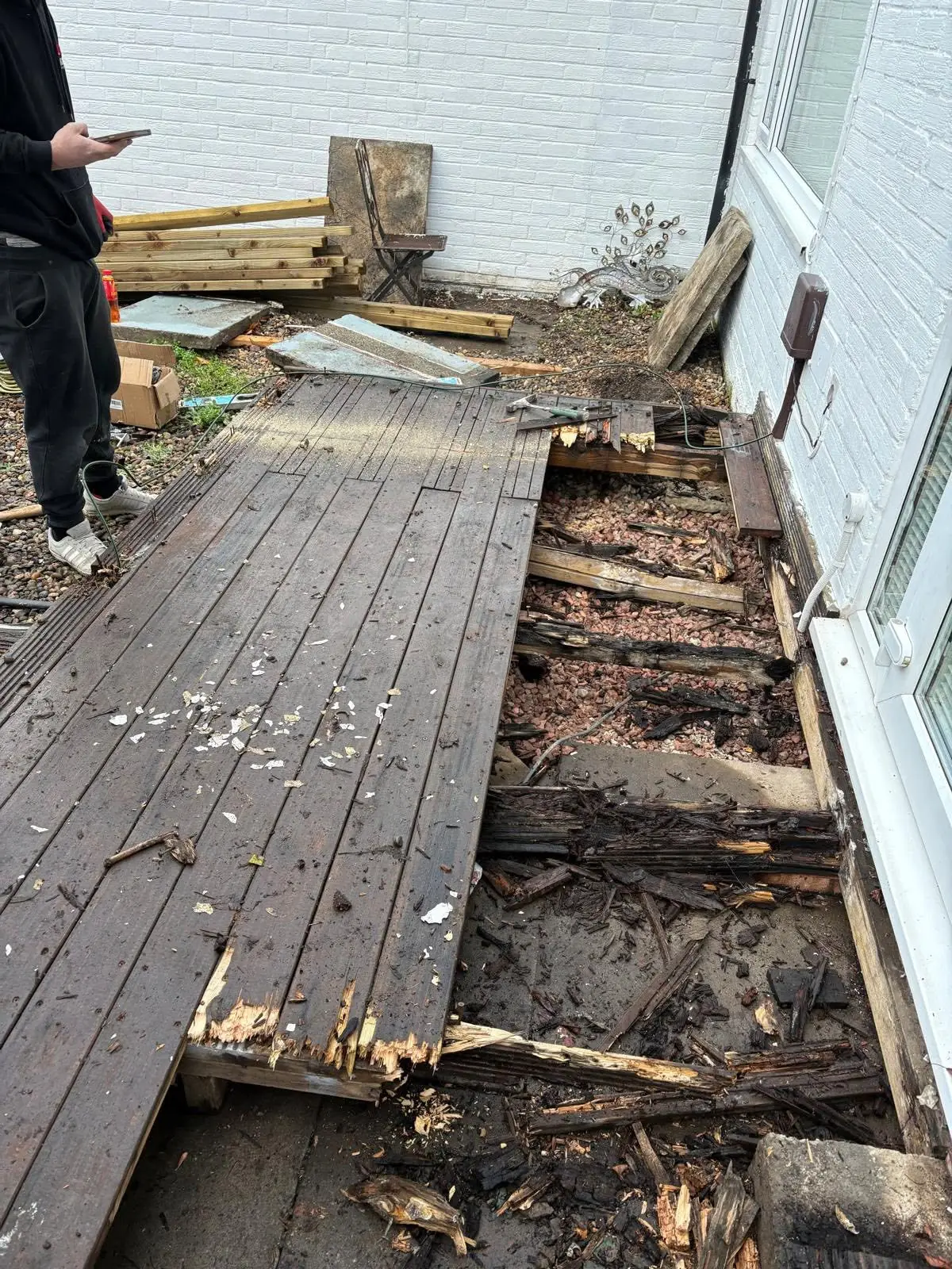 The old decking lifted, exposing rotten joists and debris underneath
