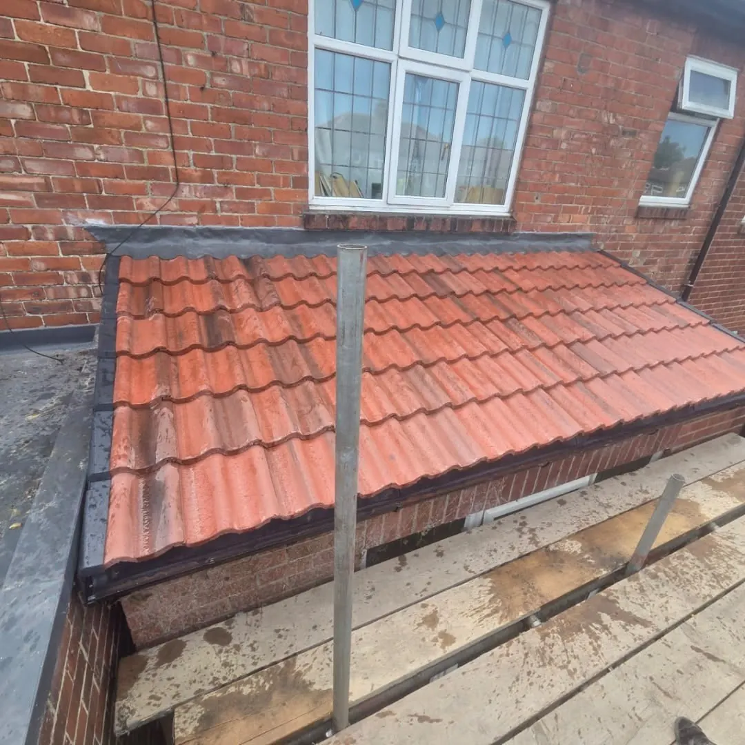 The completed low-pitch extension roof with new tiles, dark flashing and black guttering
