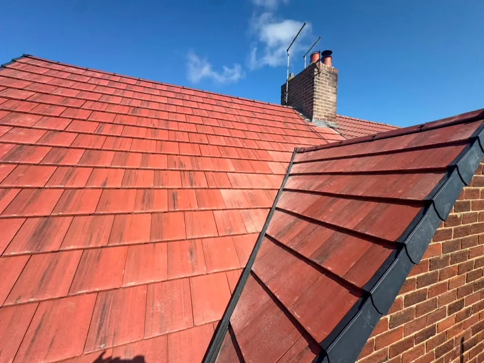 The finished roof showing the new plain tiles and dark dry verge at the gable edge